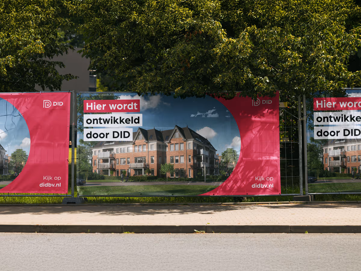 Bouwhek met doeken van DID met tekst 'Hier wordt ontwikkeld door DID' en afbeelding van appartementen.