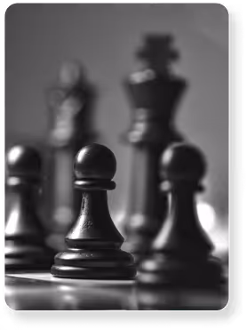 Pions d'échecs noirs au premier plan avec roi flou en arrière-plan.