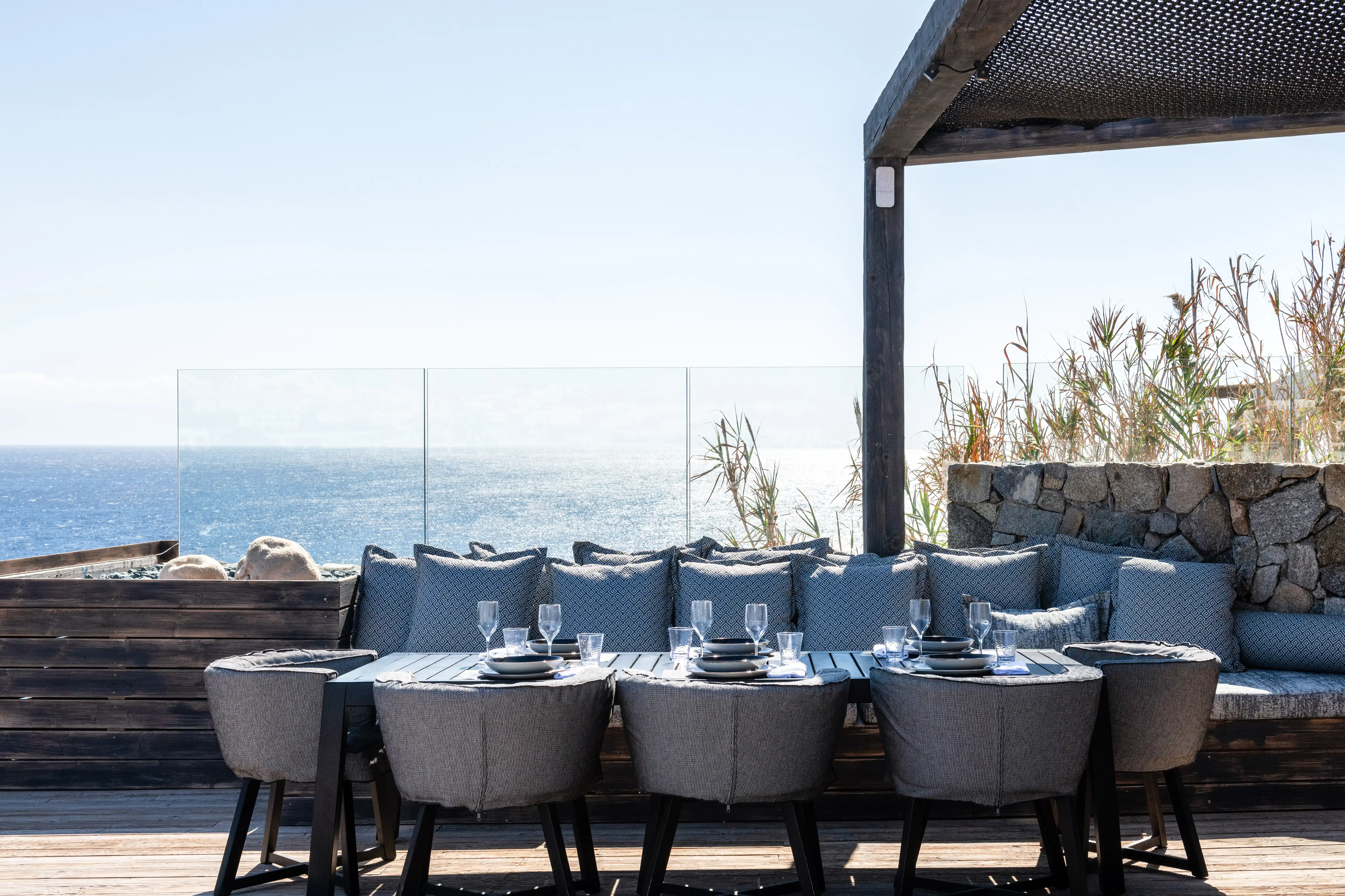 An outdoors dining table overseeing the sea.