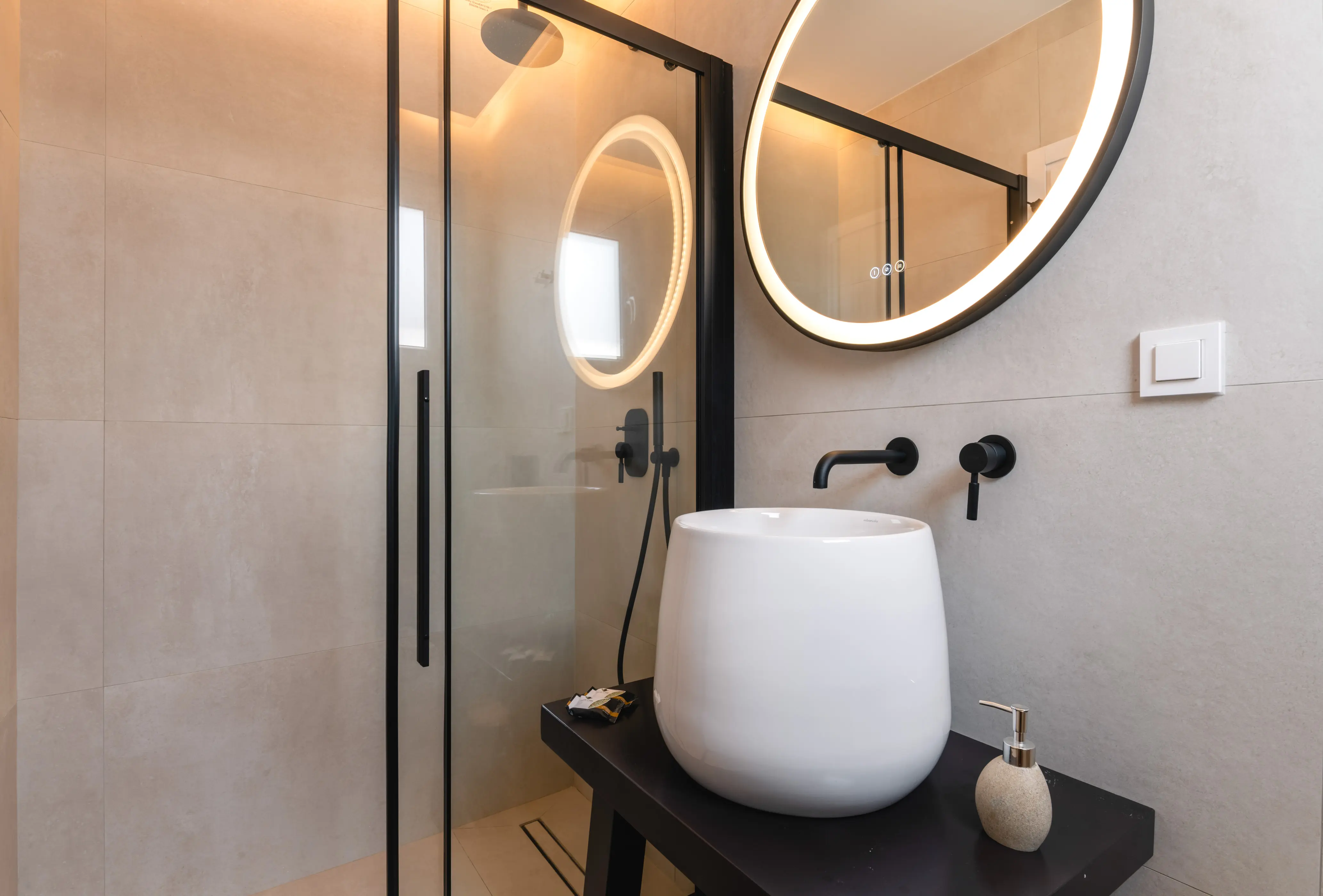 A white sink next to a shower and under a mirror.
