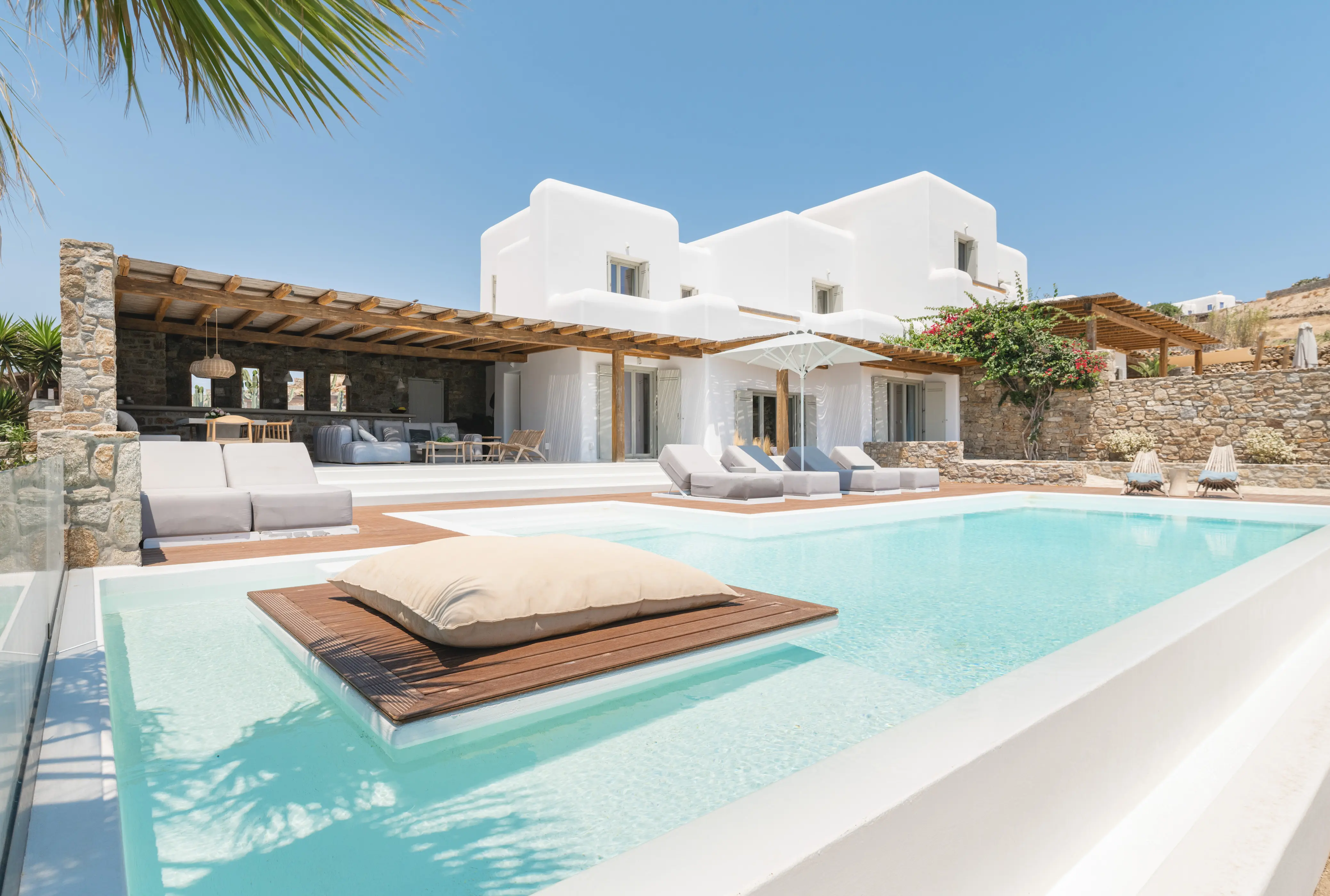 A pool infornt of a white villa.