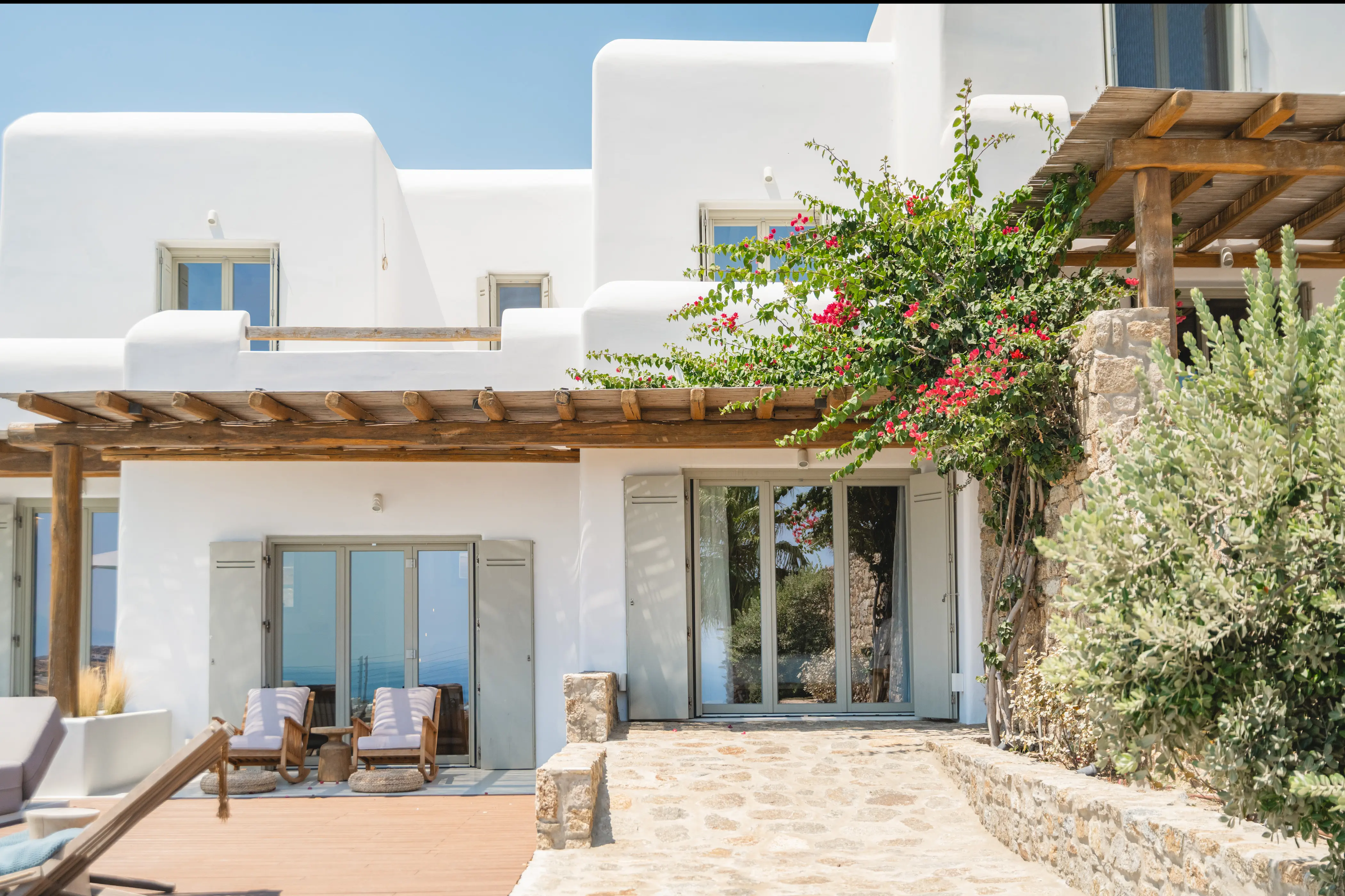 A white house with flowers and bushes.