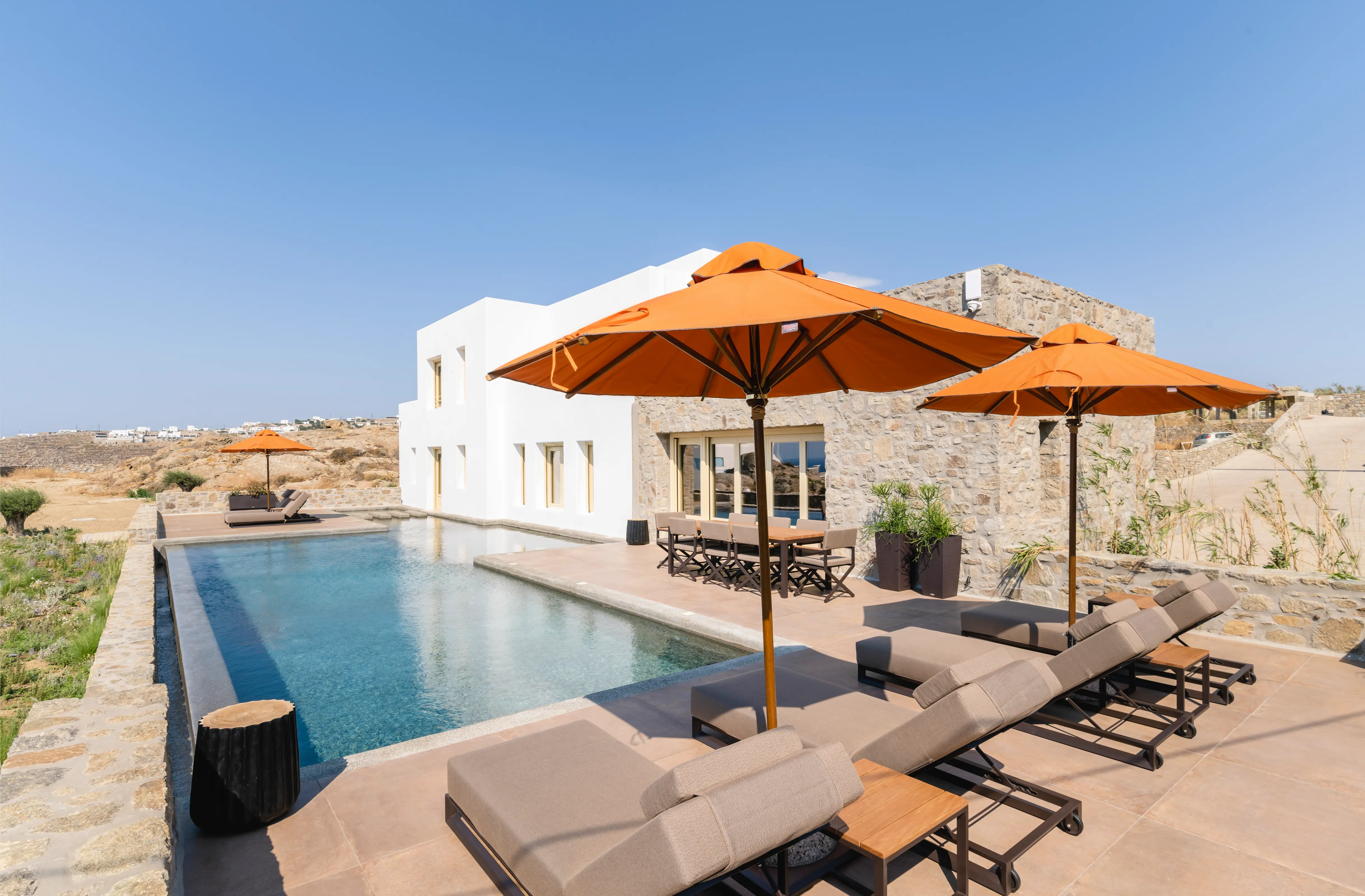 A pair of orange umbrellas, over sunbeds, overlooking the pool.