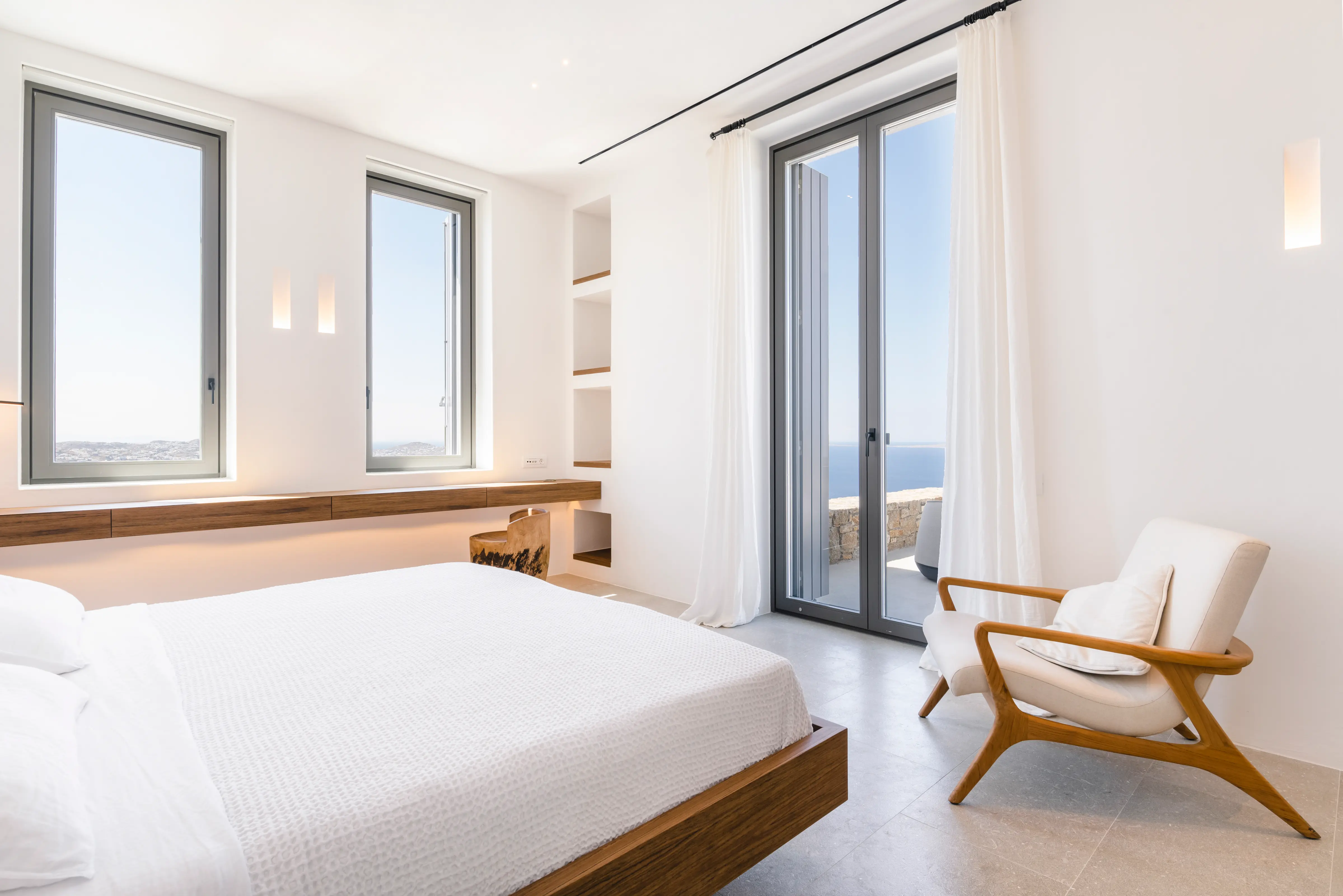 A double bed and a chair in a bedroom with views.