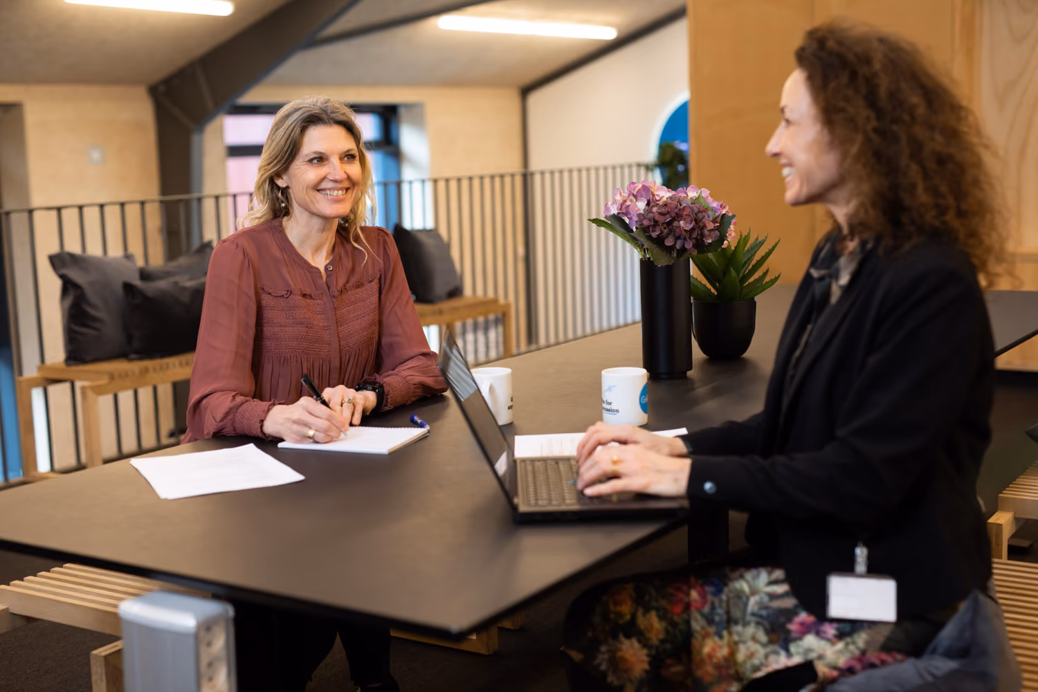 Two colleagues discussing business over laptops at a modern office table