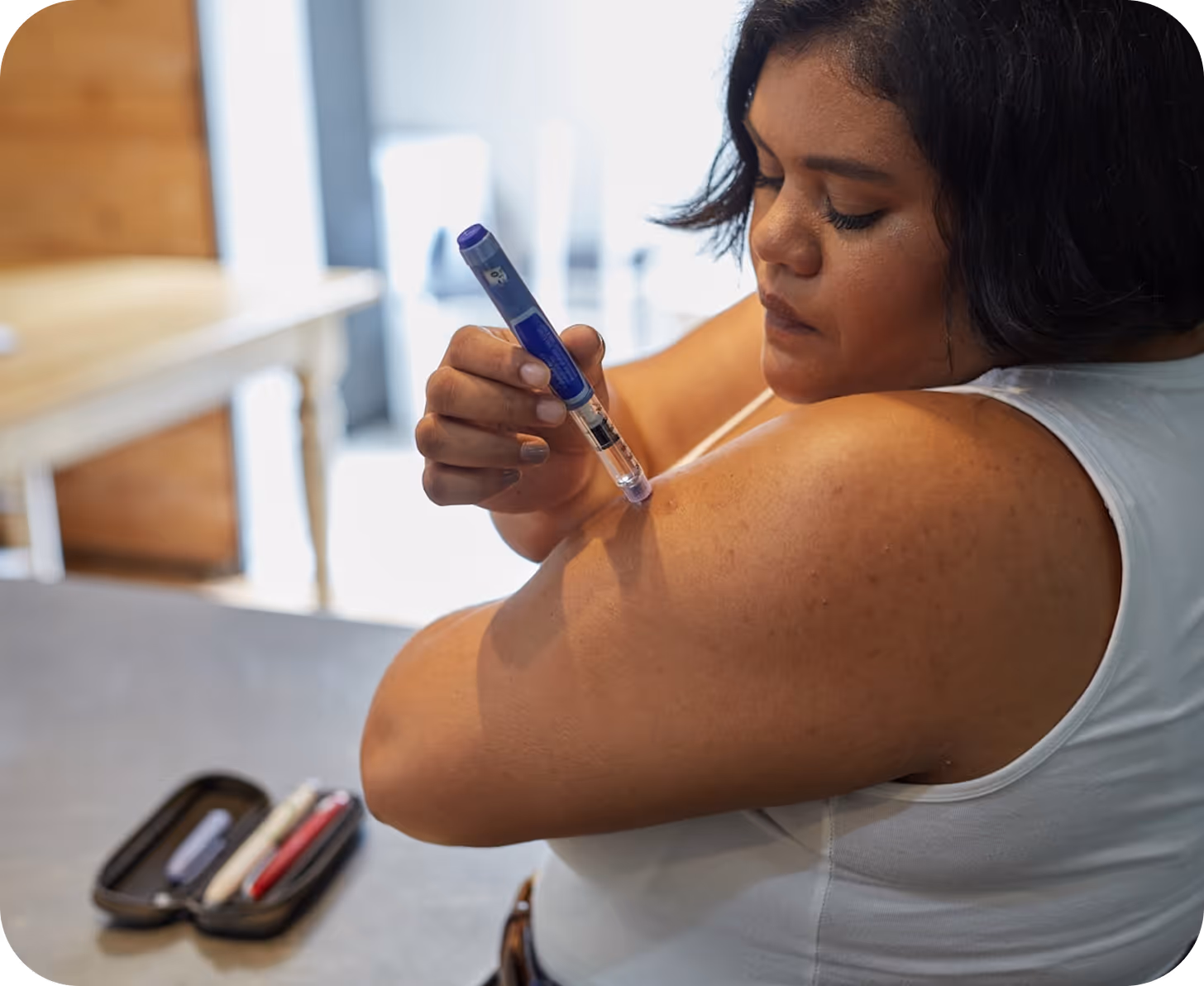 Person self-administering an injection into their upper arm using an insulin pen.