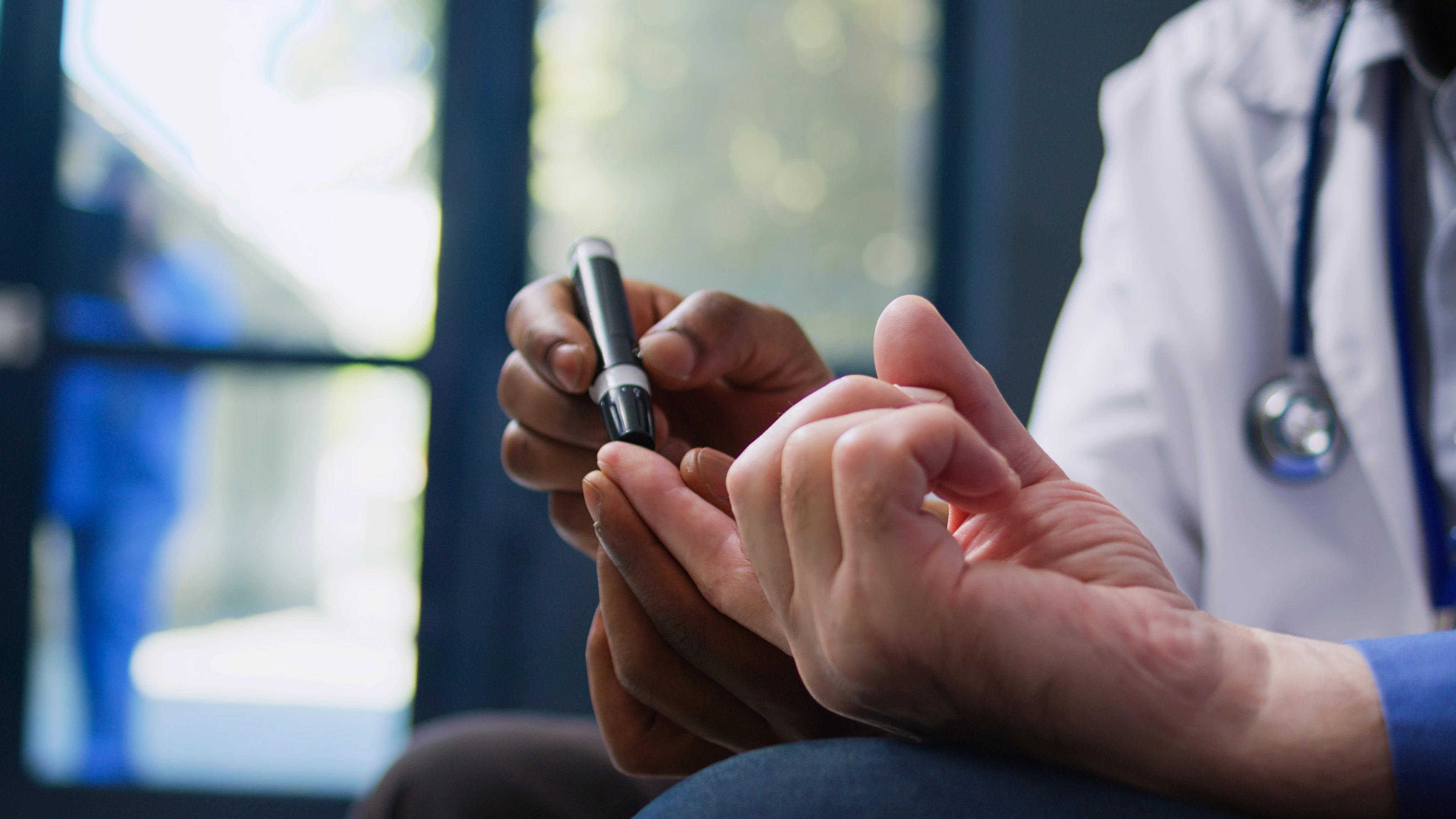 Healthcare professional using a lancet device to prick a patient's finger for blood testing.