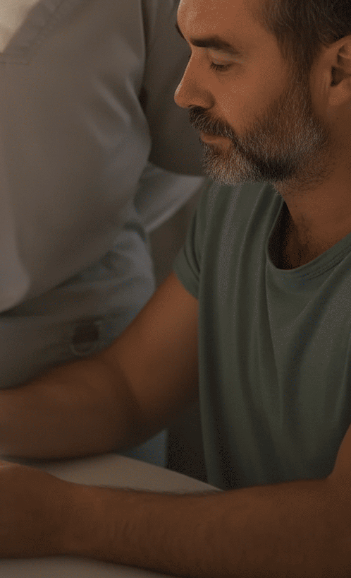 A healthcare professional using a glucometer to check a man's blood sugar level at a table.