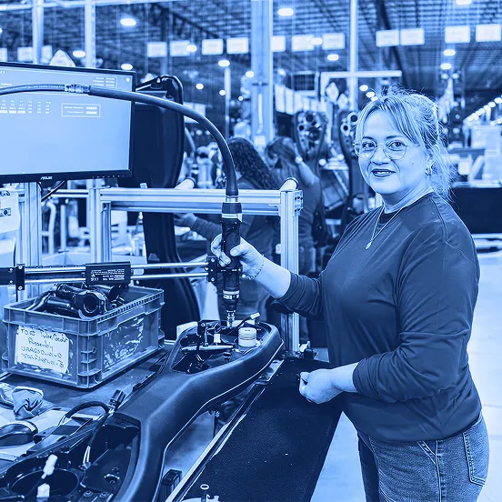 Worker operating an assembly tool at a production station on an assembly line.