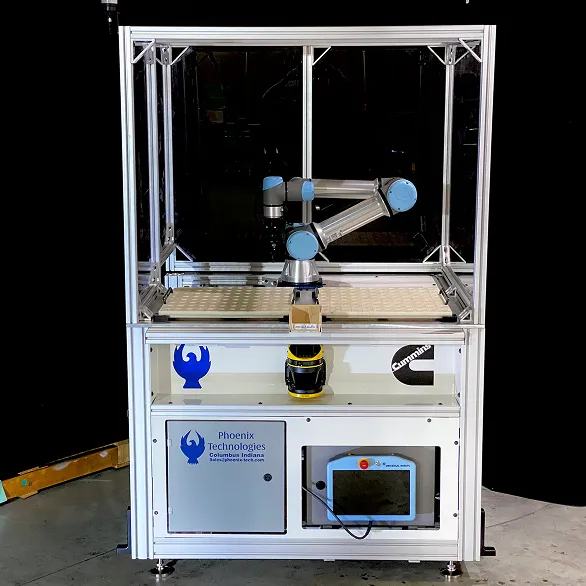 Enclosed robotic work cell with aluminum frame, clear panels, collaborative robot arm, control screen, and Phoenix Technologies logo on the front panel.