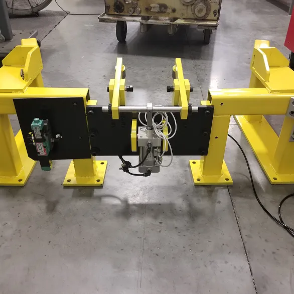 Front view of a yellow steel docking station with central pneumatic cylinder, sensor components, and mounting brackets.
