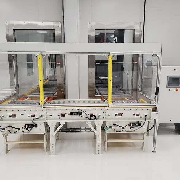 Front view of an enclosed conveyor system with clear guarding panels, yellow vertical supports, and integrated sensors beneath the conveyor.