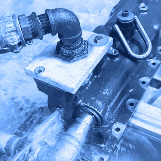 A red metal housing with attached pipes and hoses is submerged in flowing water during a test inside a metal tank.