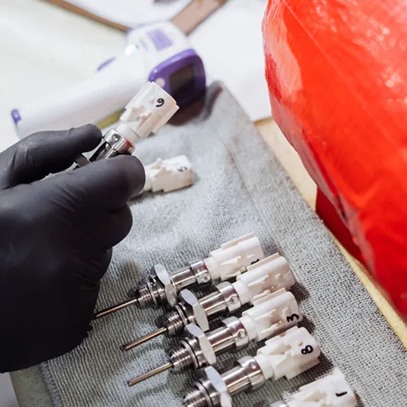 Close-up of numbered metal sensors lined up on a cloth beside a handheld infrared thermometer.
