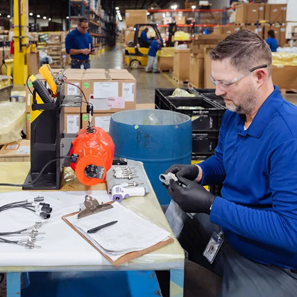 Close-up of a testing station with a red heated device, clipboard, infrared thermometer, and multiple metal sensors arranged on a cloth.