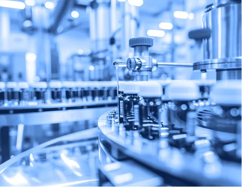 Pharmaceutical technician wearing protective clothing and holding a tablet inside a processing facility.