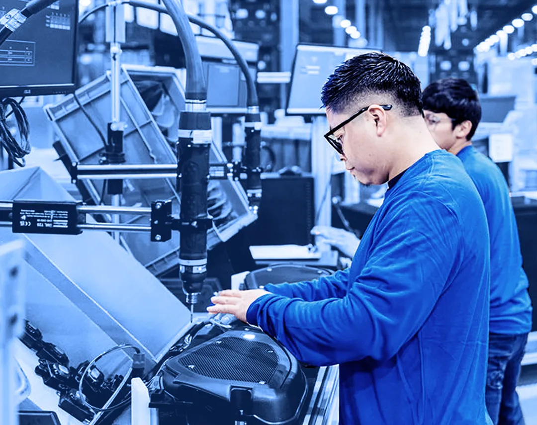 Assembly line operator working at an automated production station with conveyor equipment.