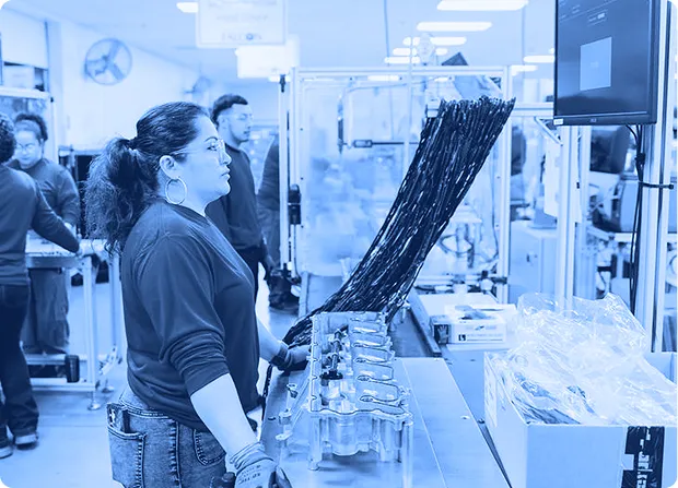 Technician monitoring automated assembly equipment and production data on a digital display.