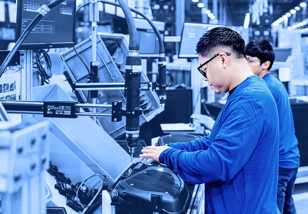 Assembly line operator working at an automated production station with conveyor equipment.
