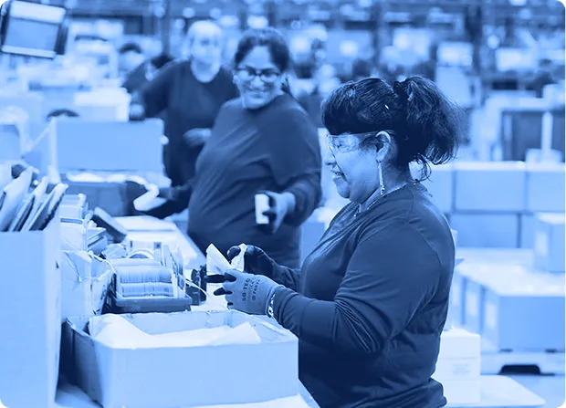 Assembly workers sorting and packaging materials at a worktable to support production flow.