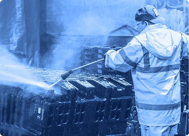 Phoenix Material employee pressure washing a large manufacturing container with spray gun