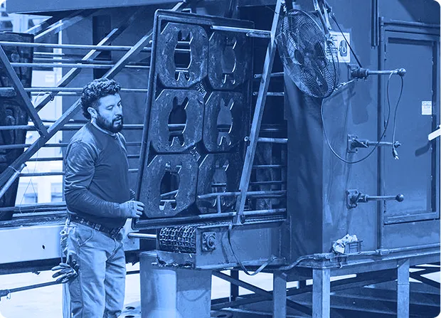 Worker loading large manufacturing container into pressure washer.