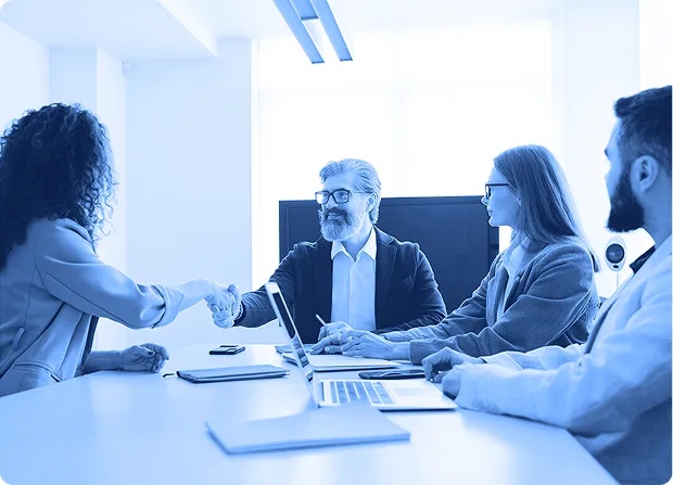 Group of professionals seated at a conference table reviewing documents during a meeting.  