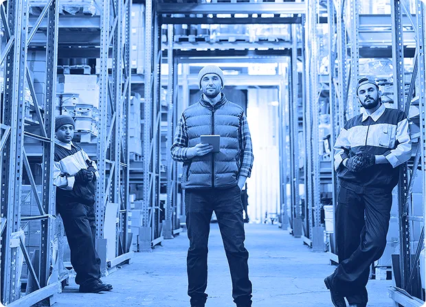 Two workers shaking hands inside an industrial facility while wearing safety gear.
