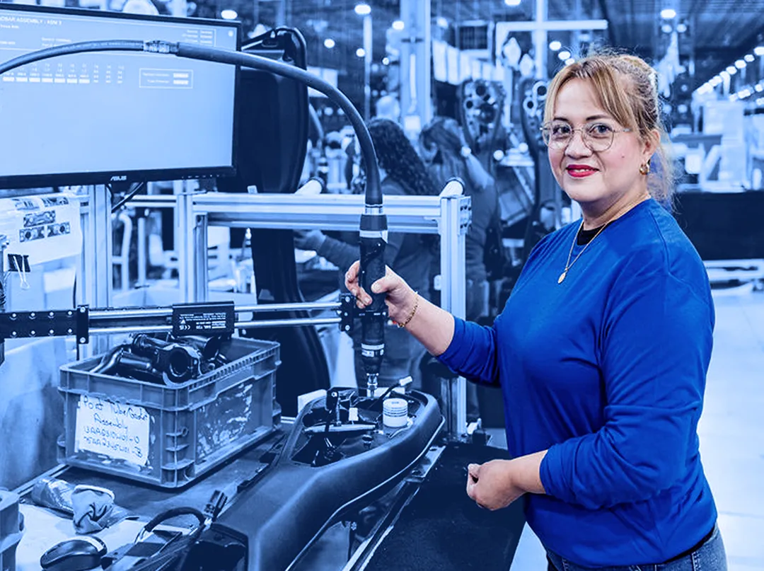 Worker operating an assembly tool at a production station on an assembly line.