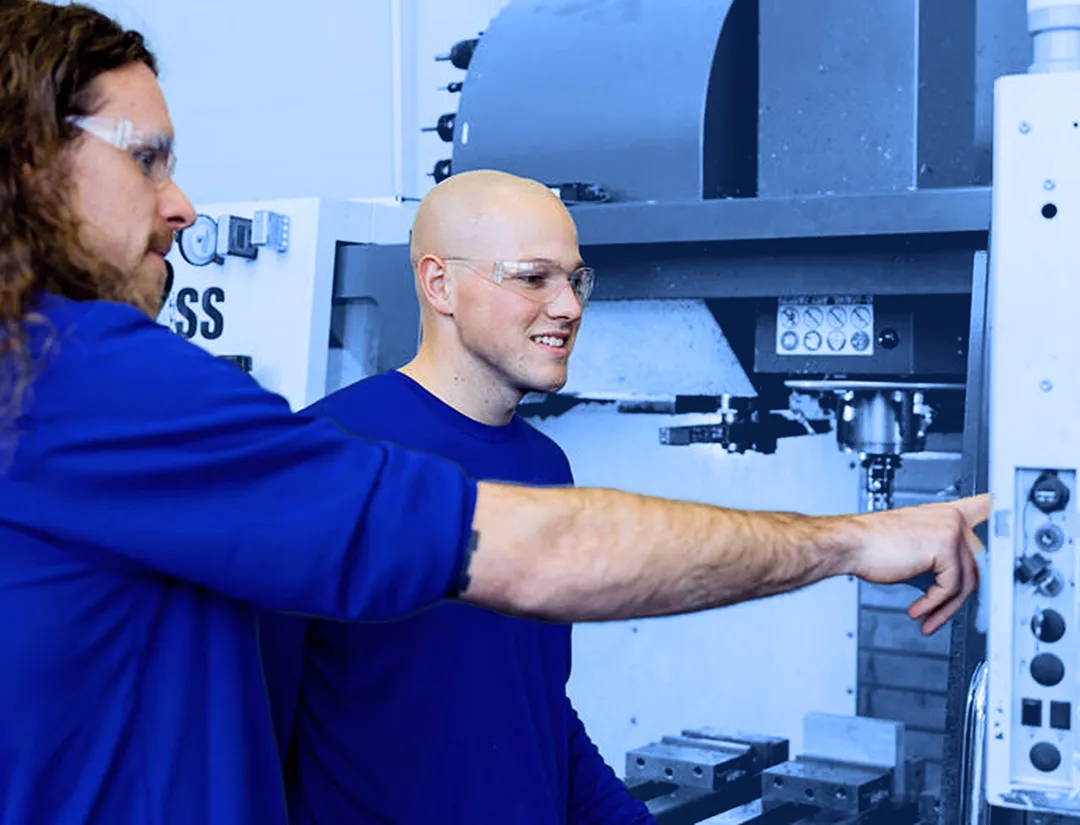 Employees seated at a conference table reviewing documents and working on laptops during a meeting.