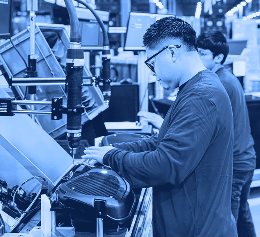 Assembly line operator working at an automated production station with conveyor equipment.