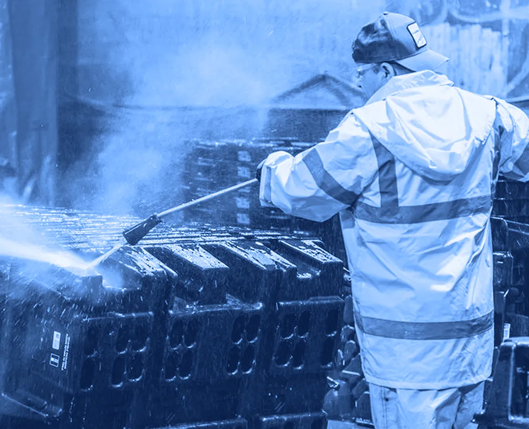Phoenix Material employee pressure washing a large manufacturing container with spray gun