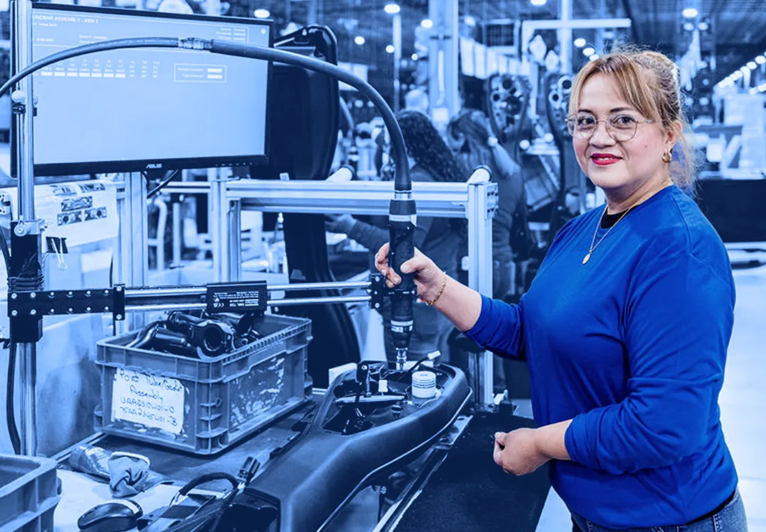 Worker operating an assembly tool at a production station on an assembly line.
