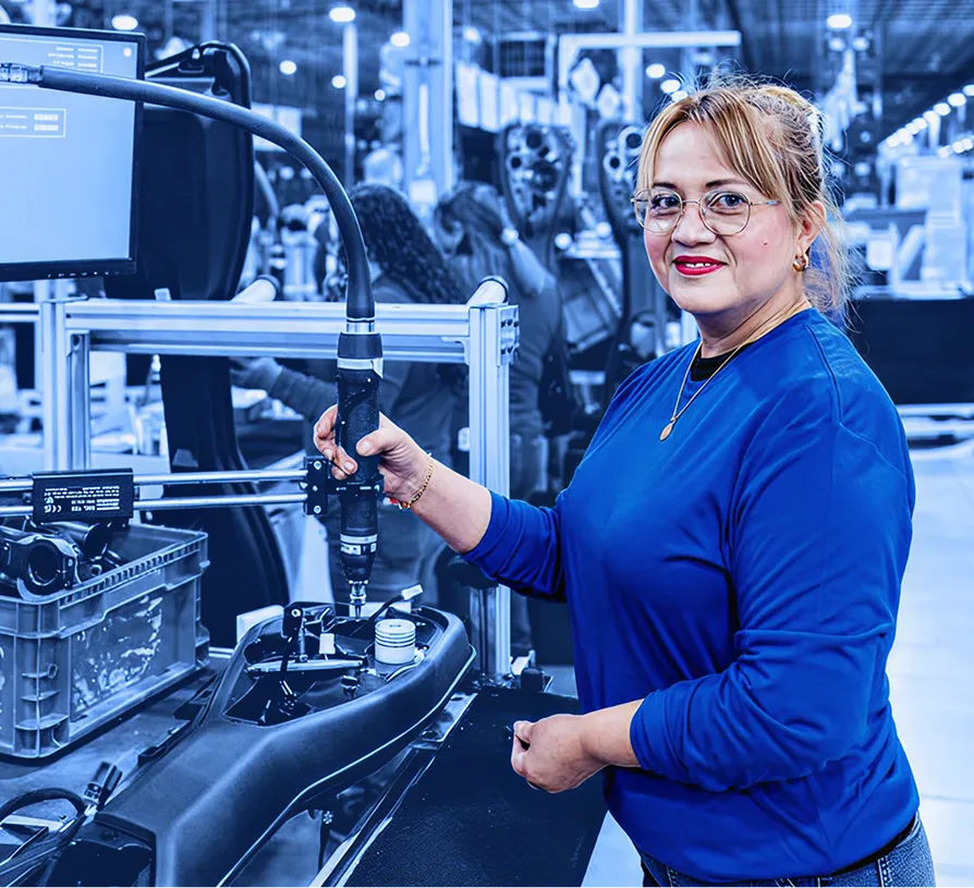 Worker operating an assembly tool at a production station on an assembly line.