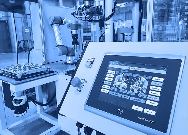 Automated robotic assembly cell with collaborative robot, fixture plate, and touchscreen control panel in a manufacturing facility.