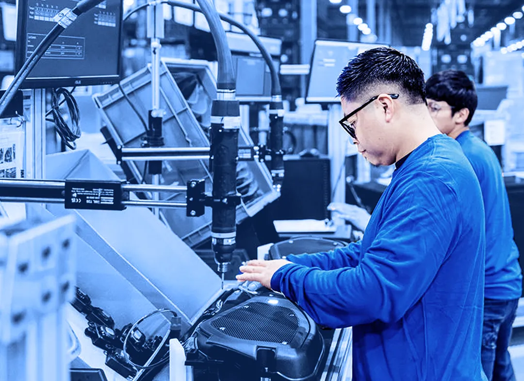 Assembly line operator working at an automated production station with conveyor equipment.
