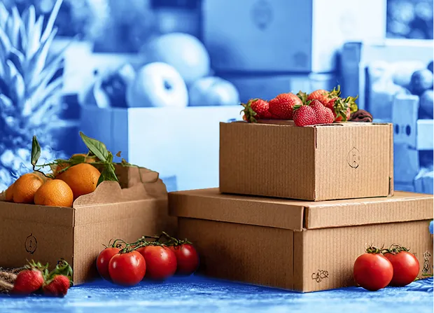 Assorted cardboard boxes filled with fresh produce including strawberries, tomatoes, apples, oranges, and leafy greens, arranged on a wooden surface with additional produce and potted plants visible in the background.