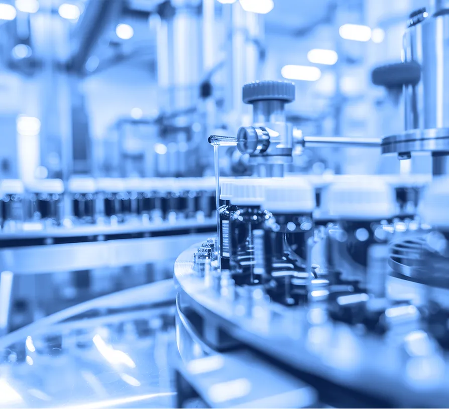 Pharmaceutical technician wearing protective clothing and holding a tablet inside a processing facility. 
