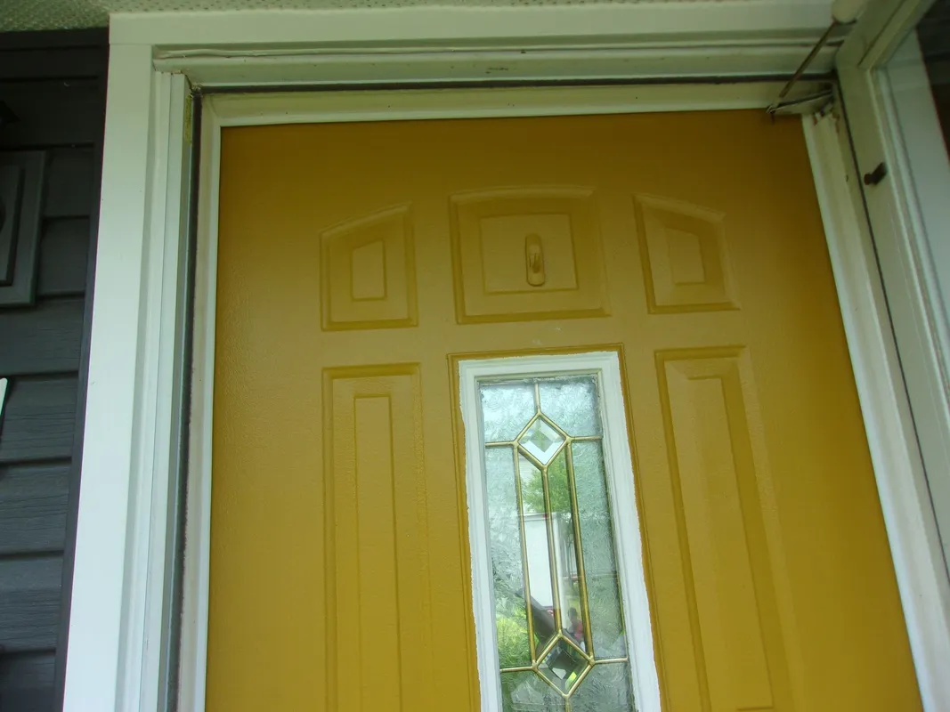 Yellow front door with decorative glass panel and white trim.