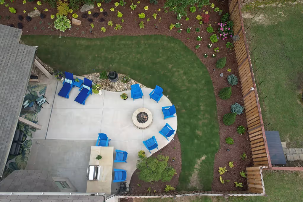 overhead drone shot of a outdoor stone fireplace next to an outdoor kitchen.