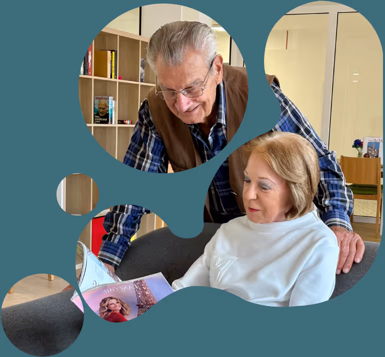 Zwei ältere Menschen sitzen am Sofa und lachen