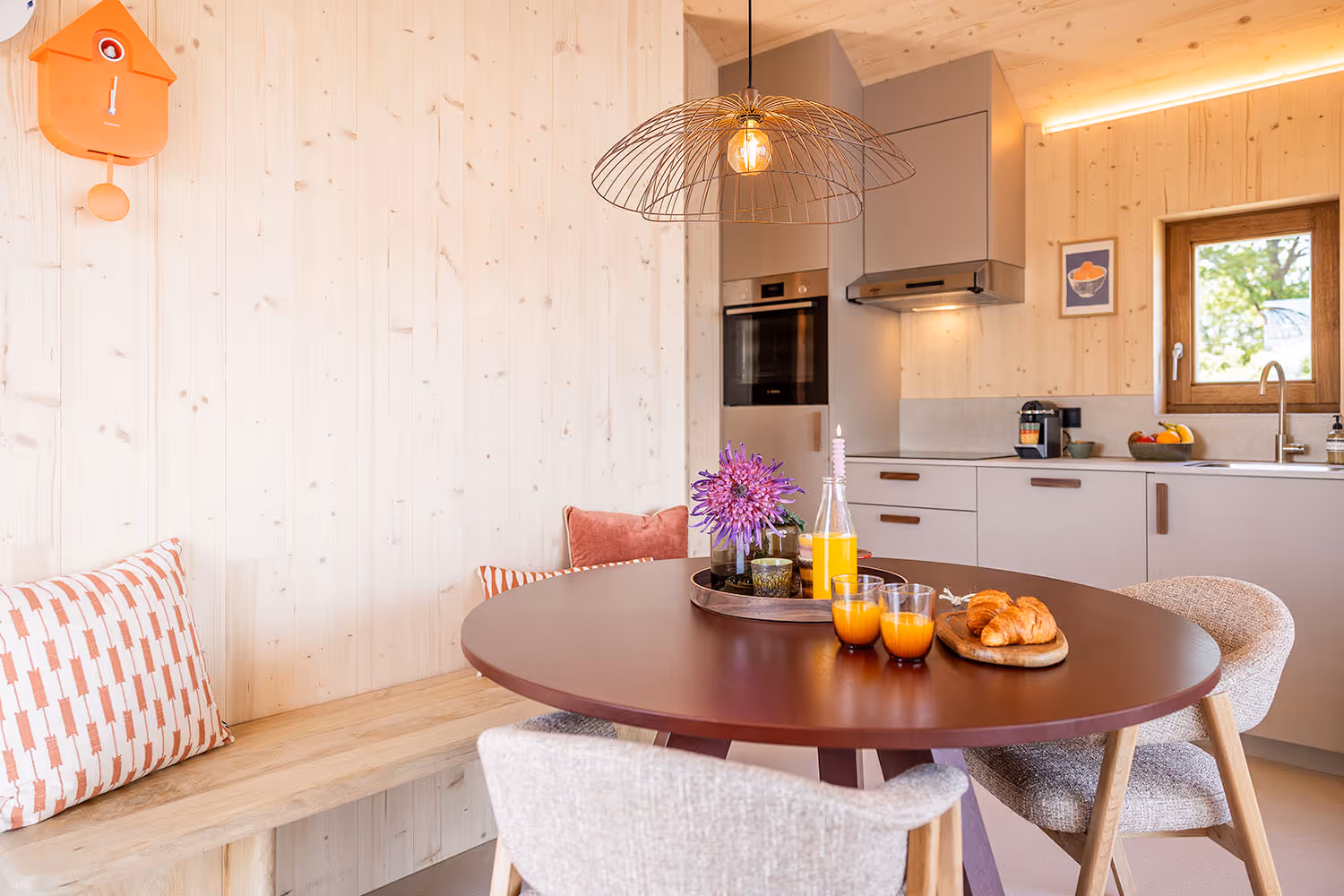 Ronde tafel in moderne keuken met croissants, sinaasappelsap en bloemen op dienblad.