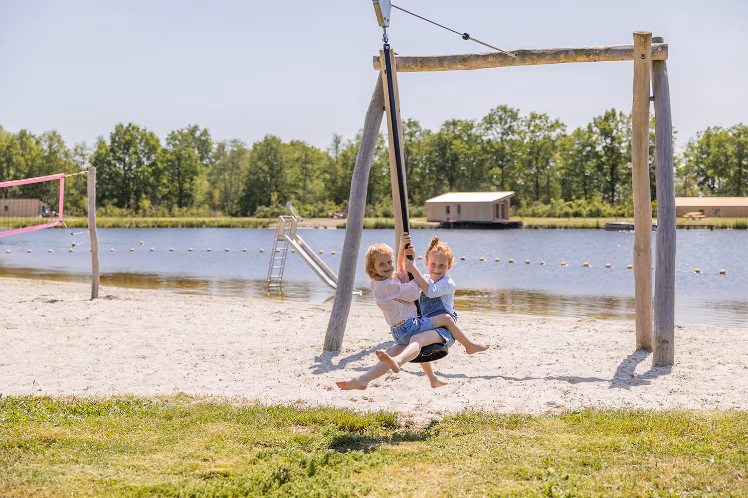Twee kinderen lachen terwijl ze samen spelen met op een kabelbaan op het strandje van Goudpoel in Oudega.