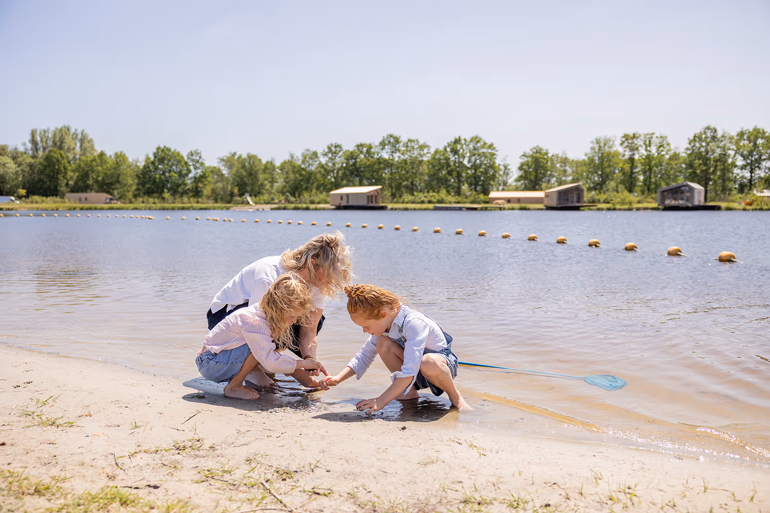 Een gezin speelt samen in het ondiepe water van het speelstrandje in Oudega bij vakantiepark Goedpoel.