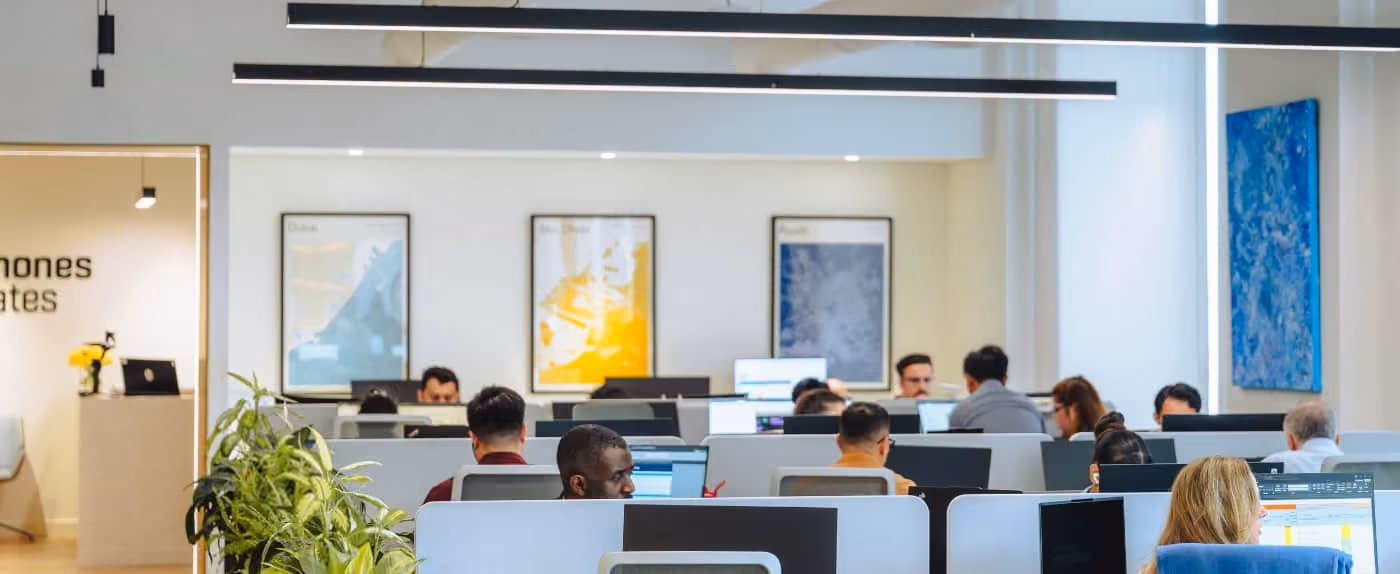 Modern open office with employees working at desks and colorful artwork on walls