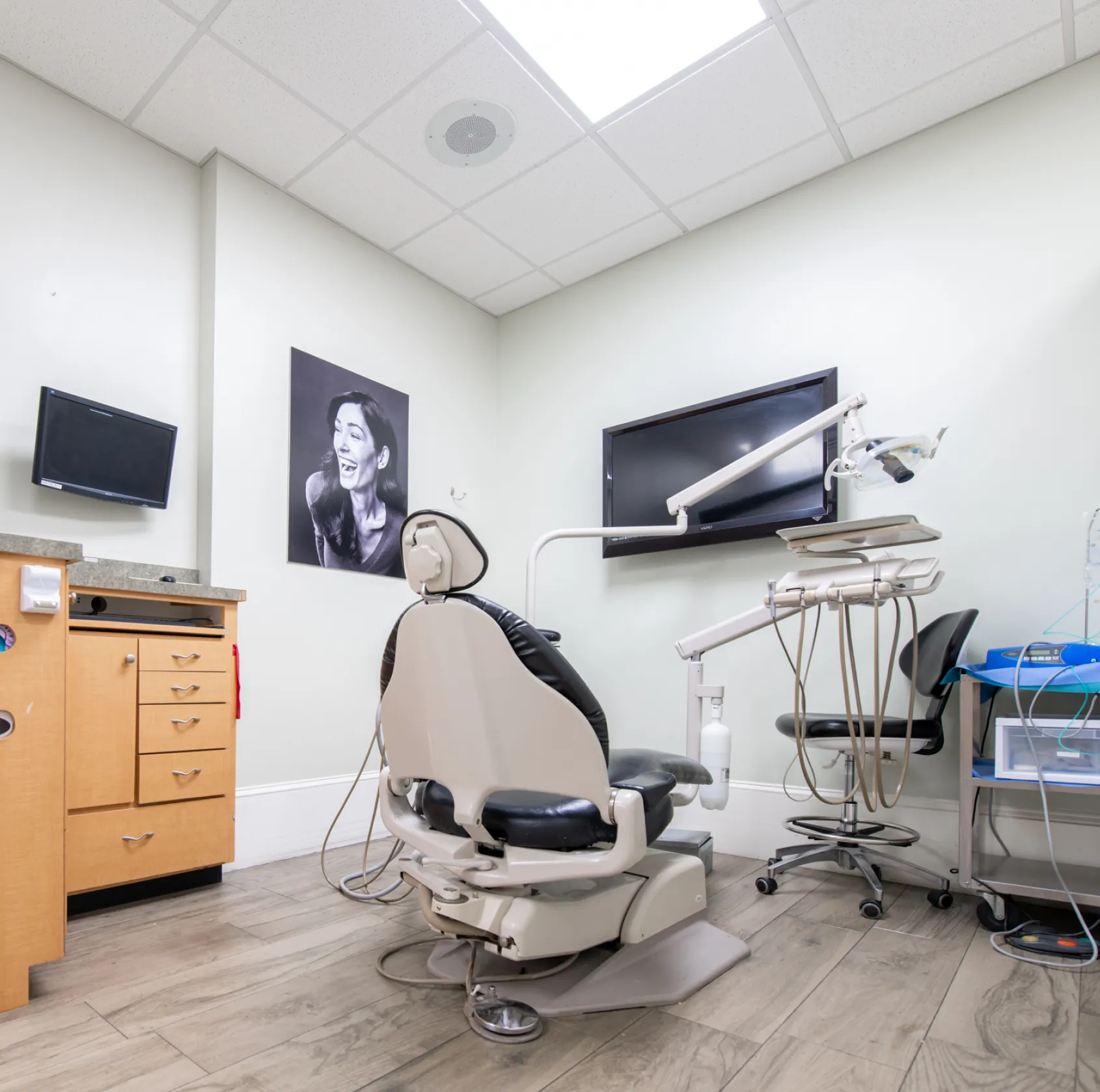 Dentist chair and equipment in a clean, modern dental office with a black-and-white photo on the wall.