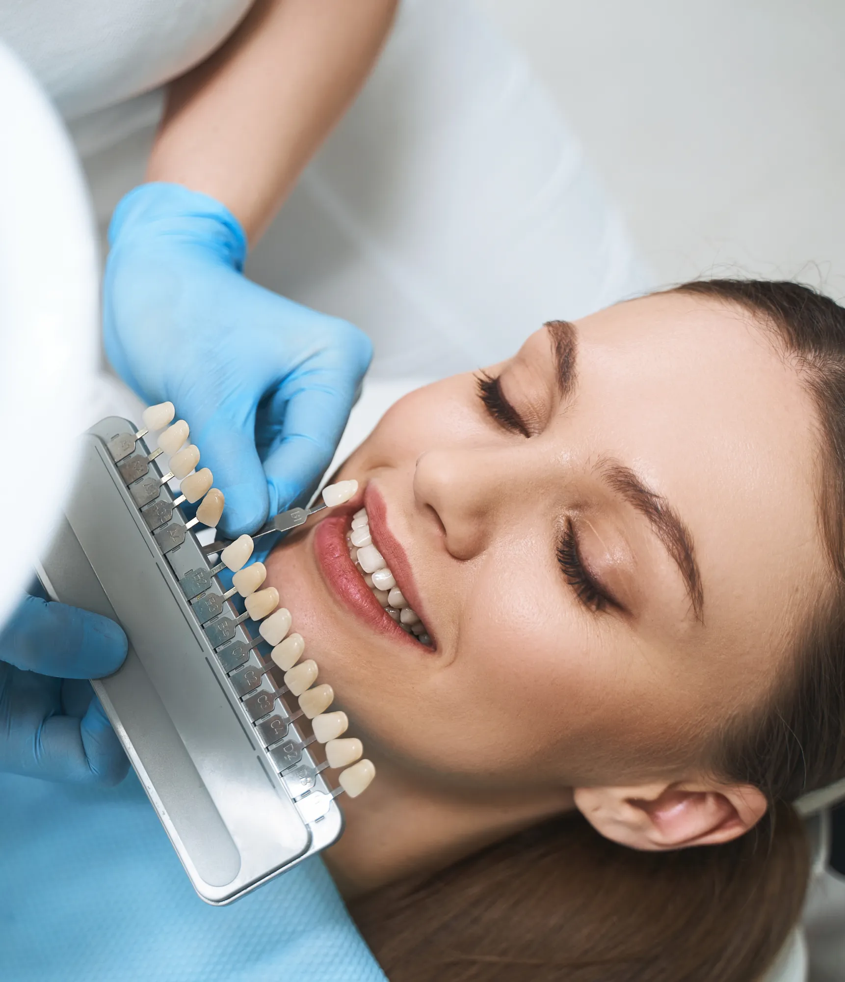 A dentist matches a patient's tooth color using a shade guide.