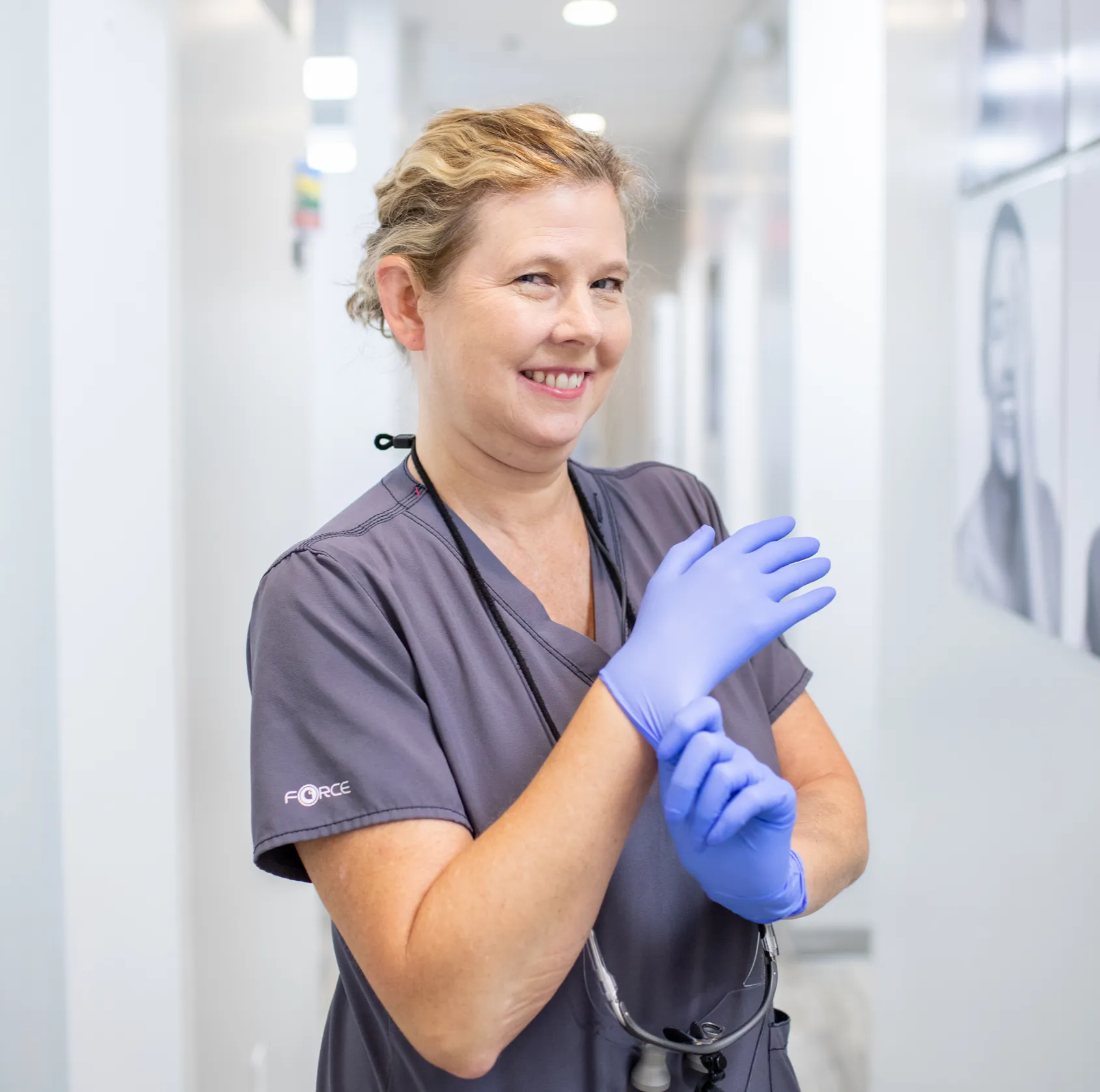 A group of people in medical uniforms pose happily, pointing towards the camera.