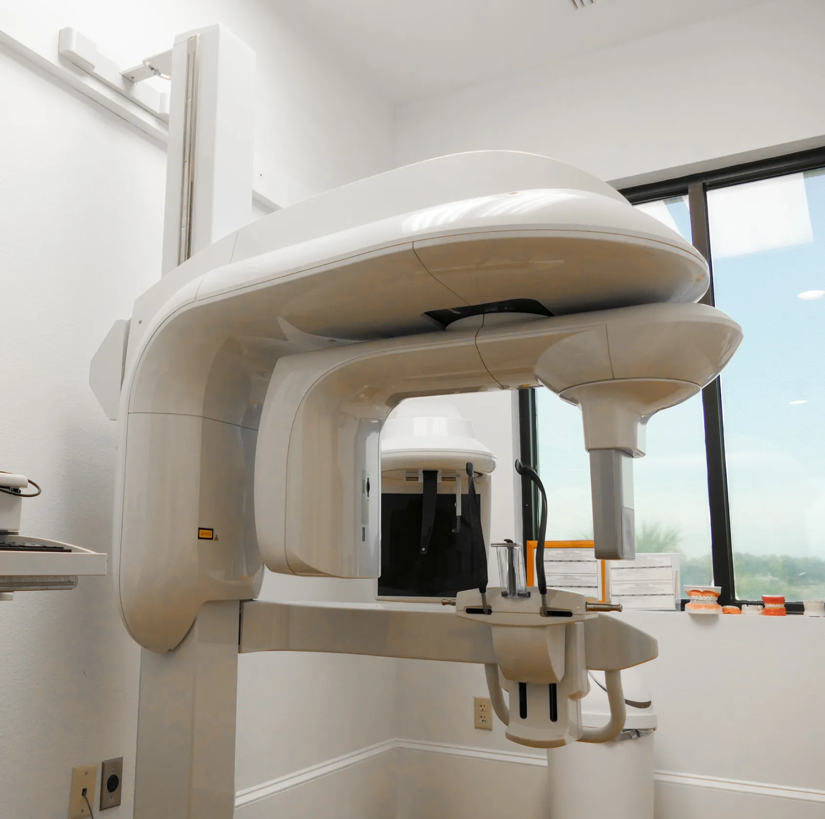 Empty waiting room with gray chairs, a small wooden table, and a TV mounted on the wall.