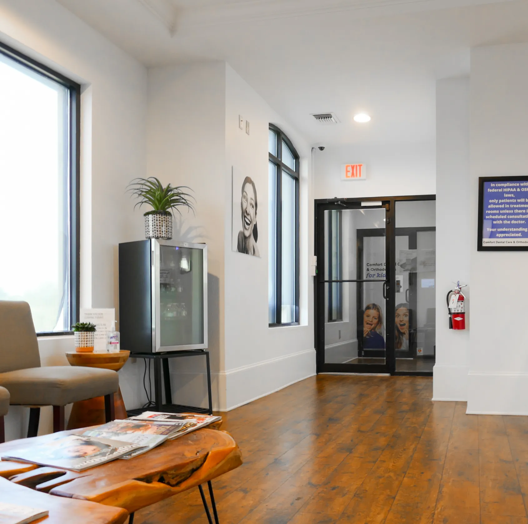 A dental care building with large windows and a palm tree in the front.